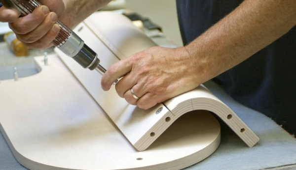Person using a drill on a wooden product with a white background