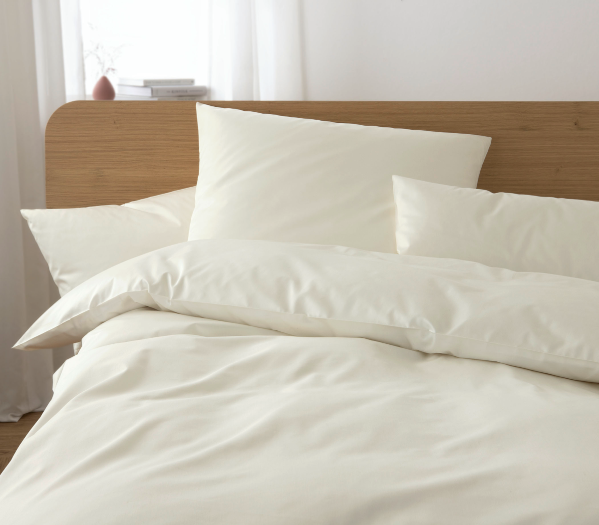 Beige bedding set on a bed with a wooden headboard.