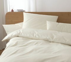 Beige bedding set on a bed with a wooden headboard.