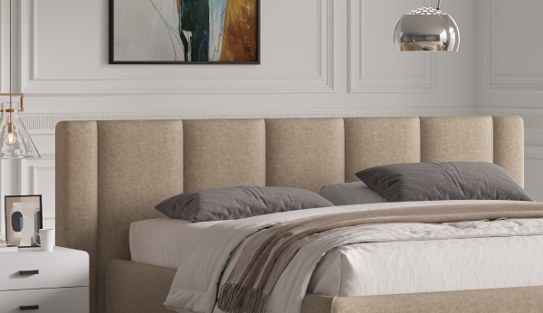 Beige upholstered bed with gray pillows in a bedroom setting.