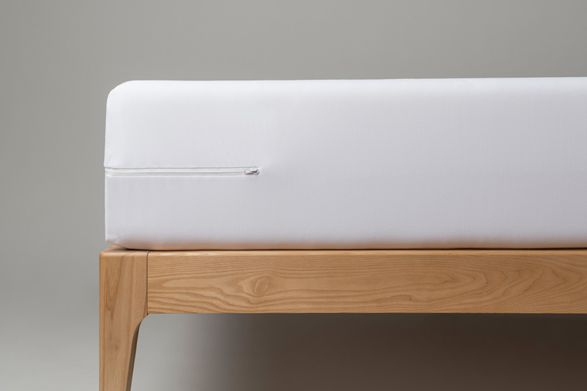 White mattress on a wooden bed frame against a gray background