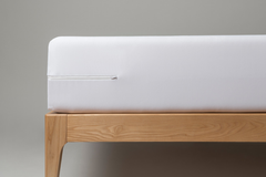 White mattress on a wooden bed frame against a gray background