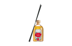 Reed diffuser with black sticks leaning on a glass bottle on a white background