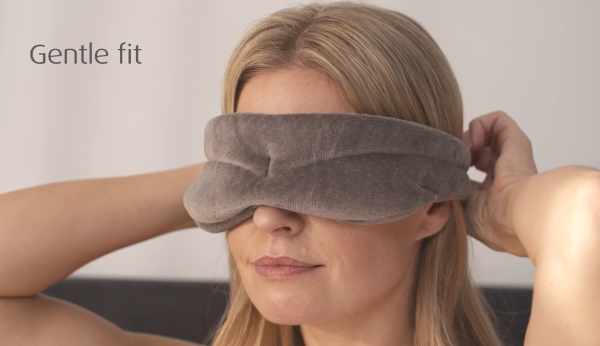 Woman wearing a gray sleep mask with 'Gentle fit' text on a plain background