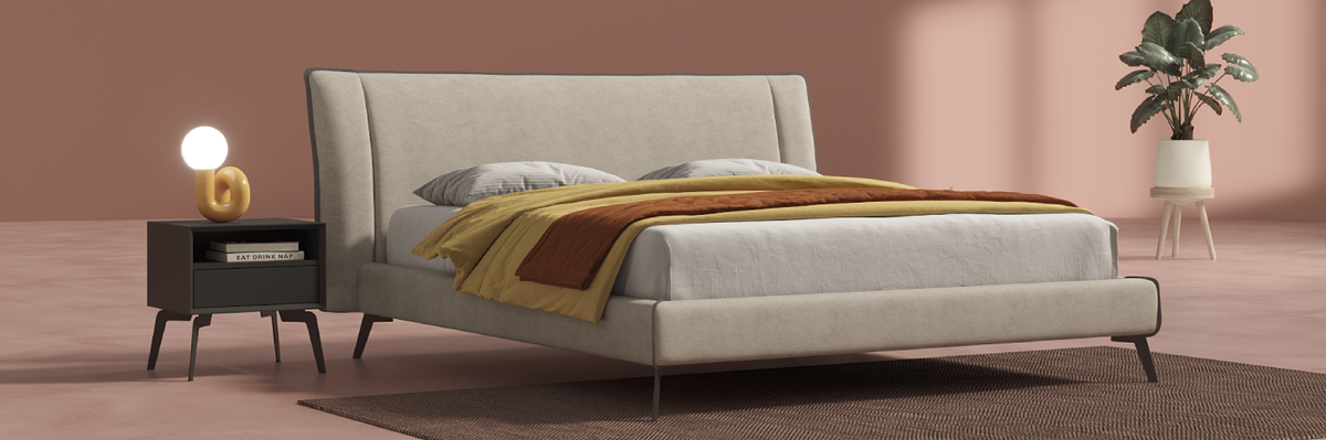 Beige upholstered bed with a side table and plant in a room with pink walls.