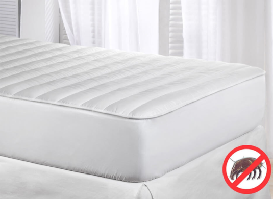 White mattress protector with a red circle and line through a mite symbol on a bed.