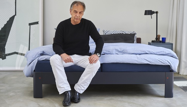 Frans de la Haye sitting on a bed in a modern bedroom setting