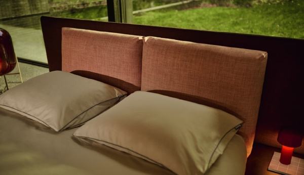 Bed with brown headboard and gray pillows in a room with a window view.