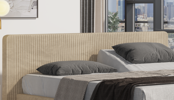 Beige upholstered headboard with gray pillows and a blanket in a bedroom setting.